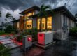 A standby generator and septic control panel outside a home during a storm.